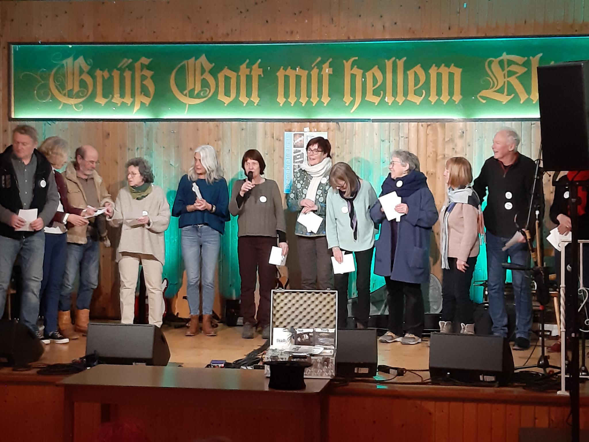 Viele Omas (und auch Opas) auf einer Bühne. In der Mitte eine Person mit Mikrofon